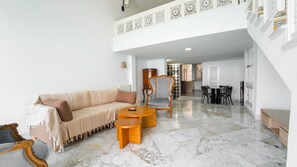 Amplia sala de estar con sofá, sillones, una mesa de centro y una mesa de comedor.