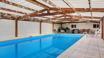 An indoor swimming pool with a tiled floor and a metal roof structure.