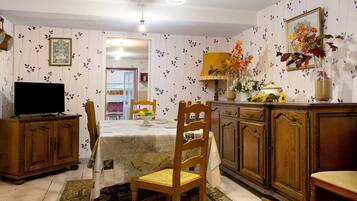 A dining area with a table, chairs, a television, and a cabinet.