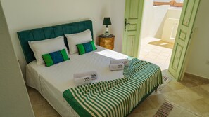 Un letto con copriletto a righe, cuscini e un comodino con una lampada.