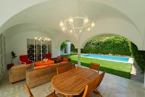 An outdoor patio with a pool, wicker furniture, and a white ceiling structure. - Villa d'exception à Gammarth – piscine privée (Gammarth)