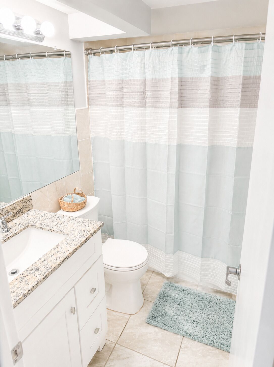 A bathroom with a shower curtain, a sink, a toilet, and a mirror.