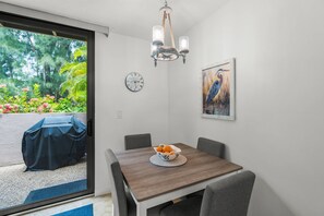 Ein Essbereich mit einem Holztisch, Stühlen, einer Obstschüssel, einer Wanduhr, einer Deckenleuchte und einem Vogelbild.