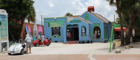 A building with a blue facade, a sign for massage therapy, and a beachwear & apparel store.