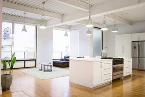 Una cocina amplia con una isla central, electrodomésticos de acero inoxidable e iluminación colgante.