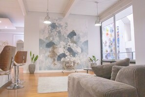 En modern inredning med en stor, abstrakt målning, en sittgrupp och utsikt över omgivningarna.
