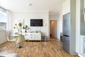 A modern kitchen with a dining area, a flat-screen TV, and a refrigerator. - Elev Cape Town Exclusive Panorama Suite (Cape Town)