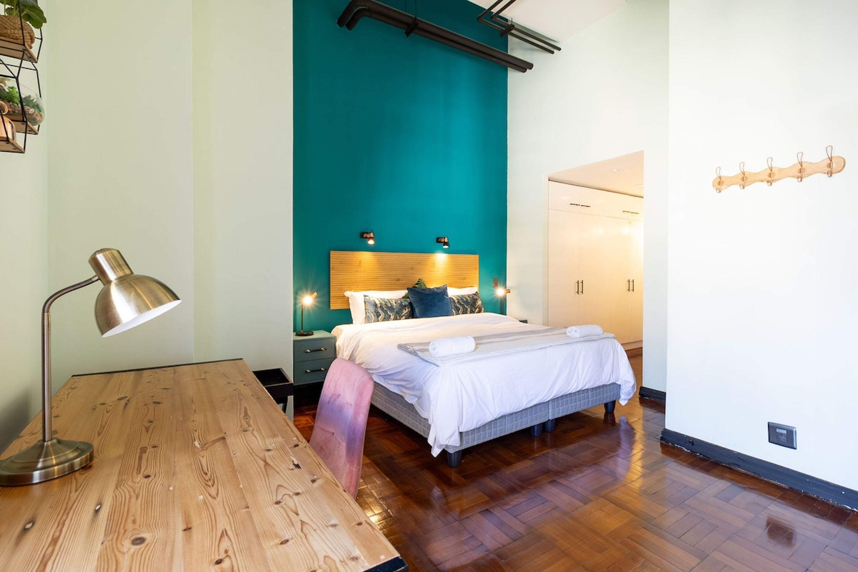 A bedroom with a bed, bedside tables, a desk, and a lamp.