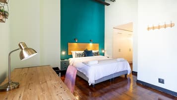 A bedroom with a bed, bedside tables, a desk, and a lamp.