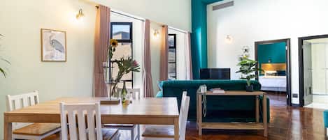 A dining area with a wooden table and chairs, a green sofa, and a chandelier.