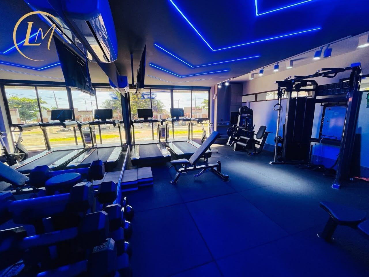 Un gimnasio con cintas de correr, máquinas de pesas y colchonetas de ejercicio.