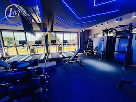 Uma academia com esteiras, máquinas de peso e colchonetes de exercícios.