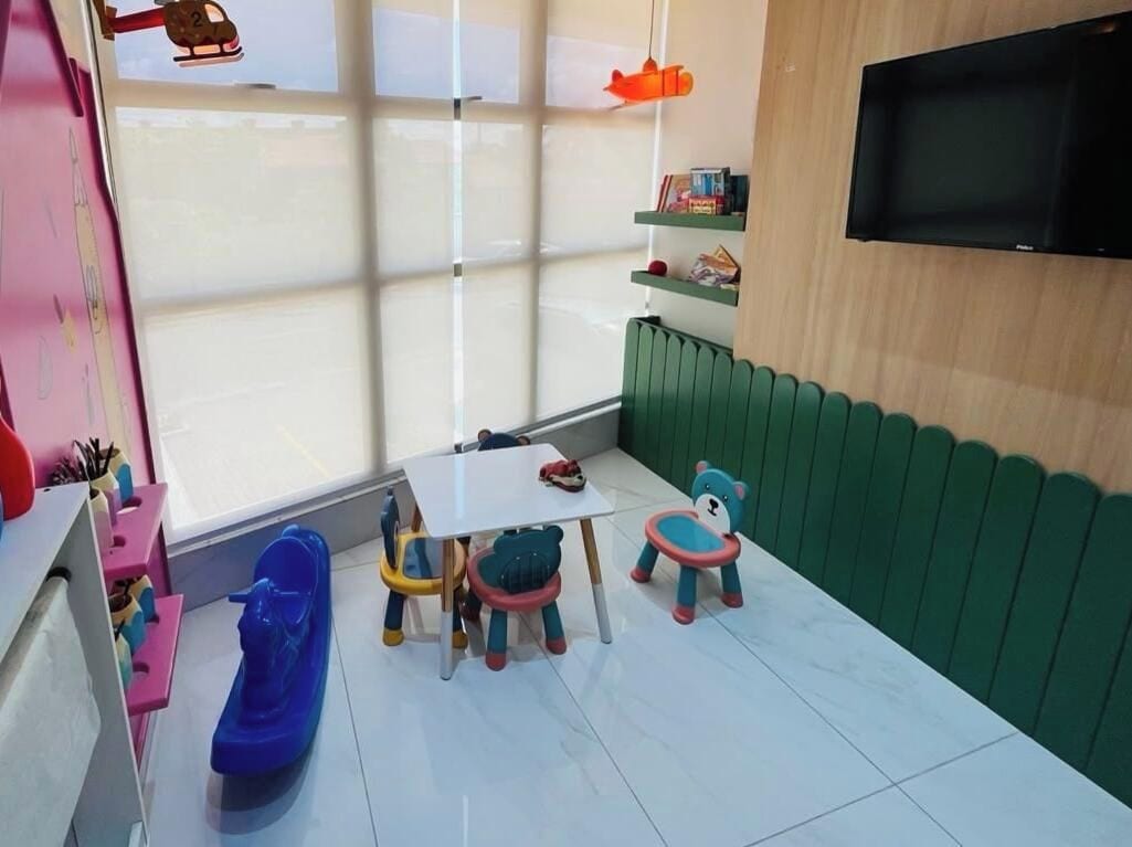 Zona de juegos infantiles con una mesa, sillas y un barco de juguete azul.