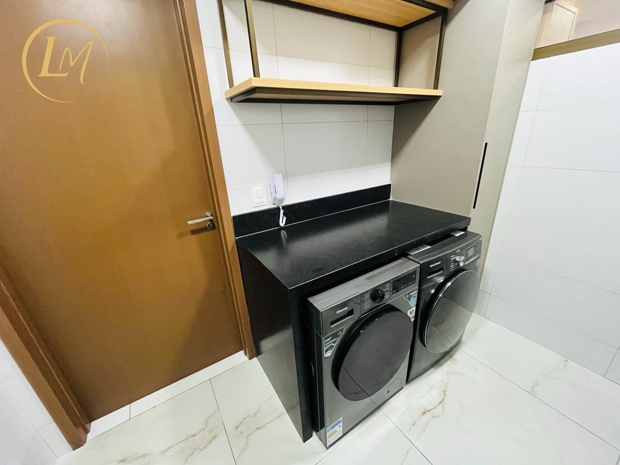 Un espacio pequeño para lavandería, con lavadora y secadora, una puerta de madera y un revoque de azulejos.