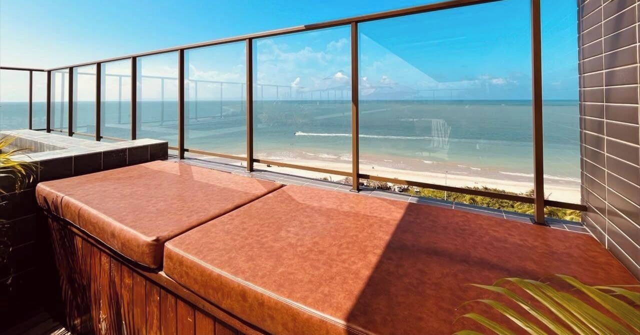 A balcony with a view of the beach and a bridge.