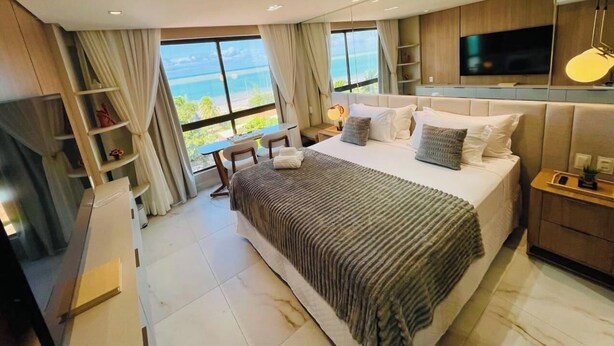 Habitación de hotel moderna con una cama grande, televisión, escritorio y vistas al océano.