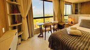 Una habitación de hotel con un ventanal grande, una cama, un escritorio y una silla.