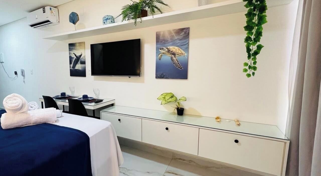 Habitación de hotel con cama, escritorio, televisor de pantalla plana y obras de arte en la pared.