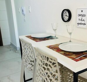 A dining area with a white table, two chairs, a clock, and a wall with a sign.