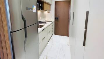 Una cocina compacta con refrigerador, lavamanos y puerta de madera.