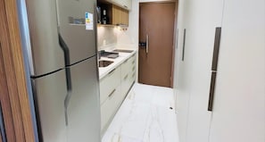 A compact kitchen with a refrigerator, sink, and wooden door. - LM DVA Cabedelo (Cabedelo)