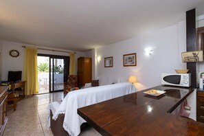 Ein Hotelzimmer mit einem Bett, einem Schreibtisch, einem Sessel, einem Fernseher, einer Mikrowelle und einem Fenster mit Vorhängen.