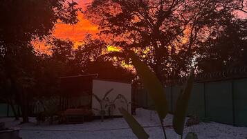 A sunset view with trees and a building in the background.