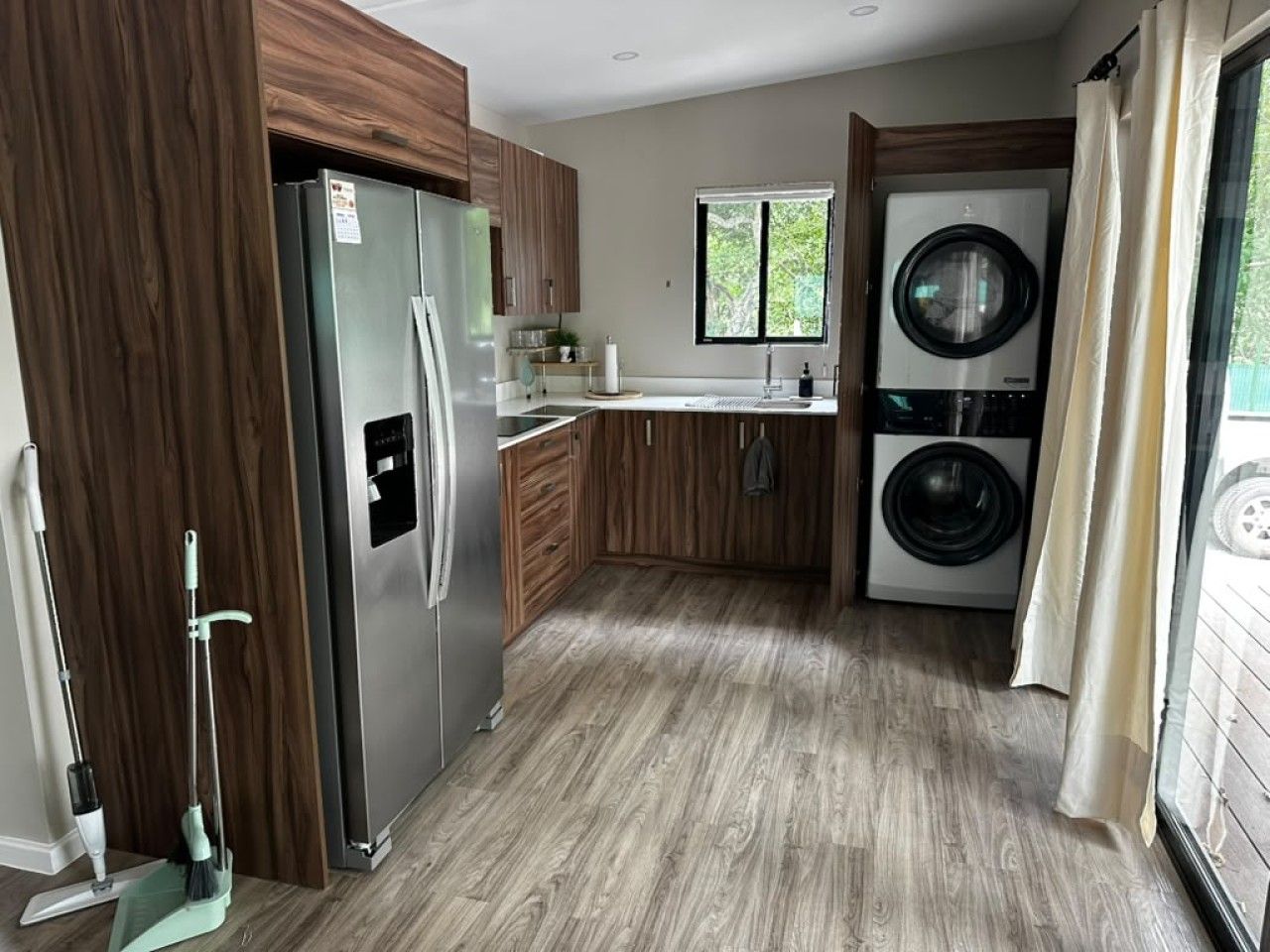 Una cucina compatta con frigorifero, lavatrice e mobili in legno.