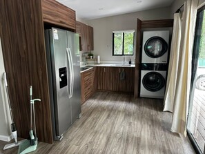 Una cucina compatta con frigorifero, lavatrice e mobili in legno.