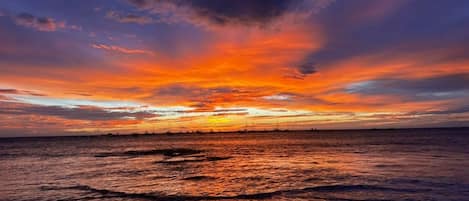 A sunset over a calm sea with a distant shoreline.