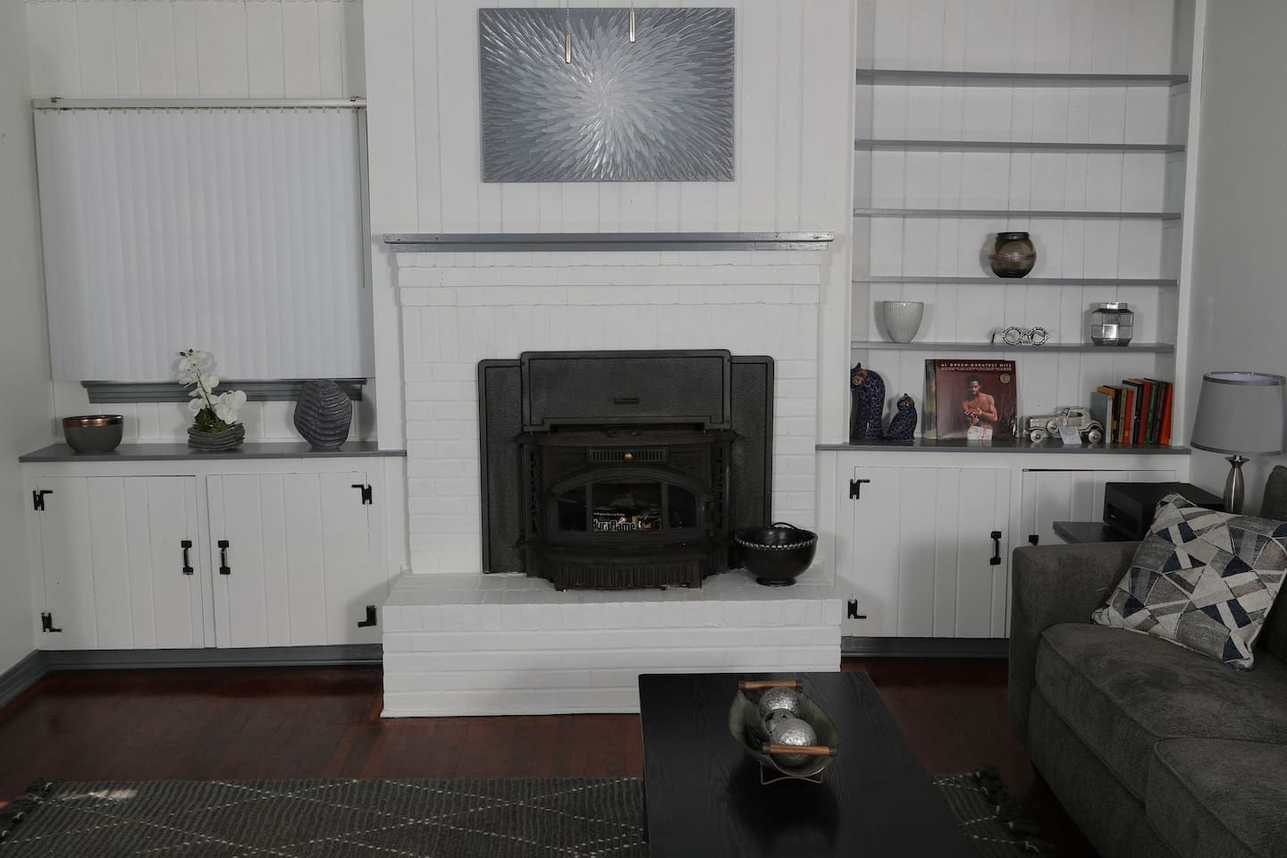 A living room with a fireplace, white cabinetry, a coffee table, and a sofa.
