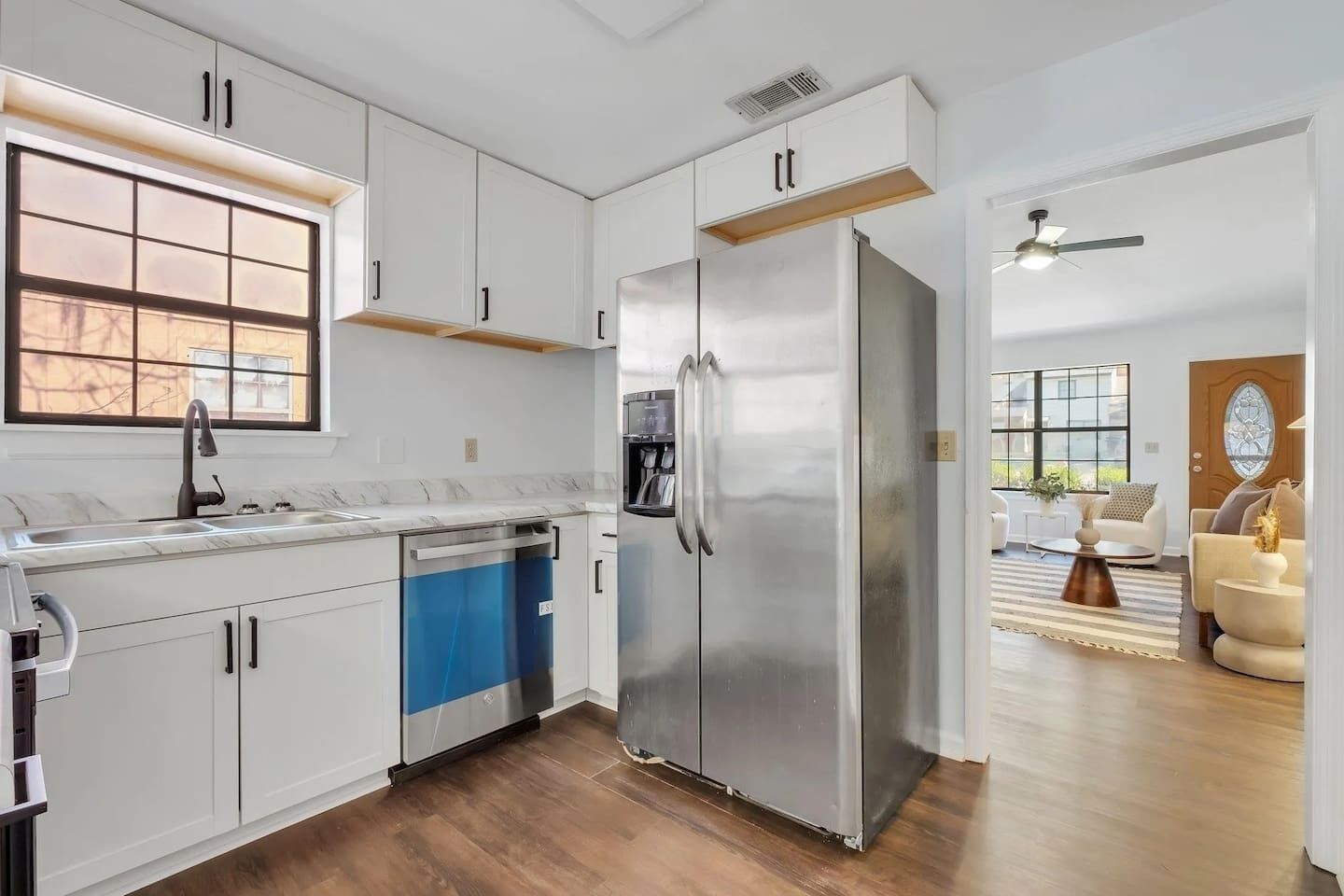 A modern kitchen with white cabinets, a stainless steel refrigerator, and a dishwasher.