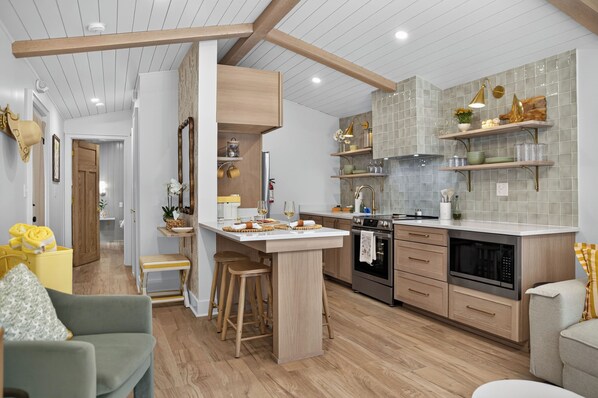 Een moderne keuken met houten kastjes, een centraal eiland en een zithoek met een bank en stoelen.