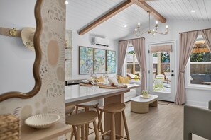 A modern interior with a kitchen area, dining space, and a view of the outdoors.