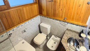 Un baño con paneles de madera, bañera, inodoro, bidé y encimera de granito con lavamanos.