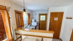 Una cocina compacta con comedor, microondas y una puerta de madera con un letrero.