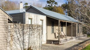 A single-story house with a covered porch, a chimney, and a small garden area. - RIVER HOUSE - MODERN COUNTRY HOME, LAURISTON (Lauriston)