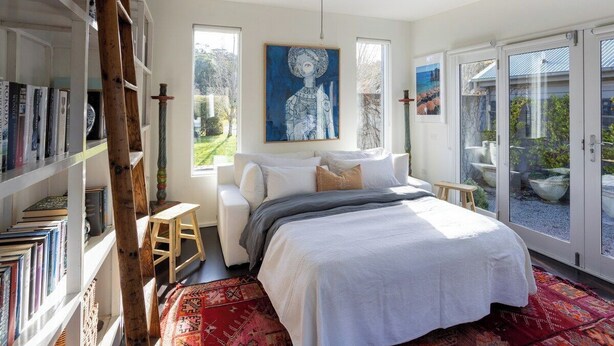 A bedroom with a bed, a bookshelf, a ladder, and a large window. - RIVER HOUSE - MODERN COUNTRY HOME, LAURISTON (Lauriston)