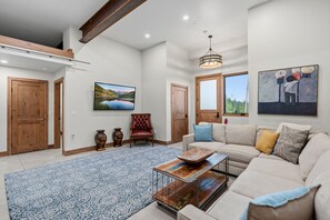 A spacious living room with a high ceiling, a large window, a sofa, a coffee table, and a fireplace. - Vista - The Best View in Breckenridge (Breckenridge)