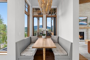 A modern dining area with a bench seating arrangement, a wooden table, and a decorative chandelier. - Vista - The Best View in Breckenridge (Breckenridge)