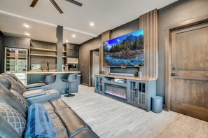 Un salon moderne doté d’un grand téléviseur à écran plat, d’une cheminée intégrée et d’un coin salon confortable.