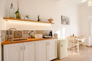 A kitchen with a wooden countertop, white cabinets, a sink, and a dining area with a table and chairs. - ALL Vecchia Bari | Historic Charm in the Heart of Old Town (Bari)