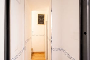 A hallway with a staircase leading to a room, a sign on the wall, and decorative patterns on the walls. - ALL Vecchia Bari | Historic Charm in the Heart of Old Town (Bari)