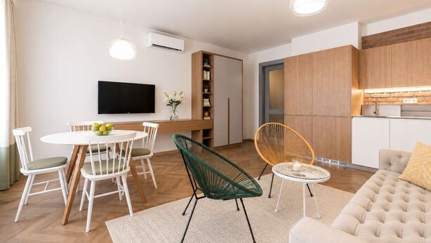 A modern living room with a sofa, dining table, chairs, and a TV. - Modern City Apartment (Prague 2)