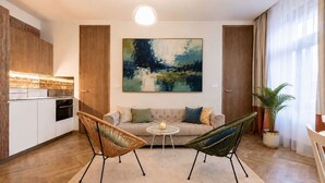 A modern living room with a sofa, two chairs, a small table, and a painting on the wall. - Modern City Apartment (Prague 2)