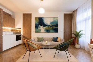 Ein modernes Wohnzimmer mit einer Couch, zwei Sesseln, einem kleinen Tisch und einem Gemälde an der Wand.
