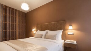 A hotel room with a large bed, two bedside tables, and a wall-mounted light fixture. - Modern City Apartment (Prague 2)