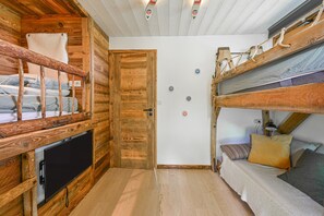Ein kleines Zimmer mit einem Etagenbett, einem Fernseher und einer Tür mit Hinweisschildern.