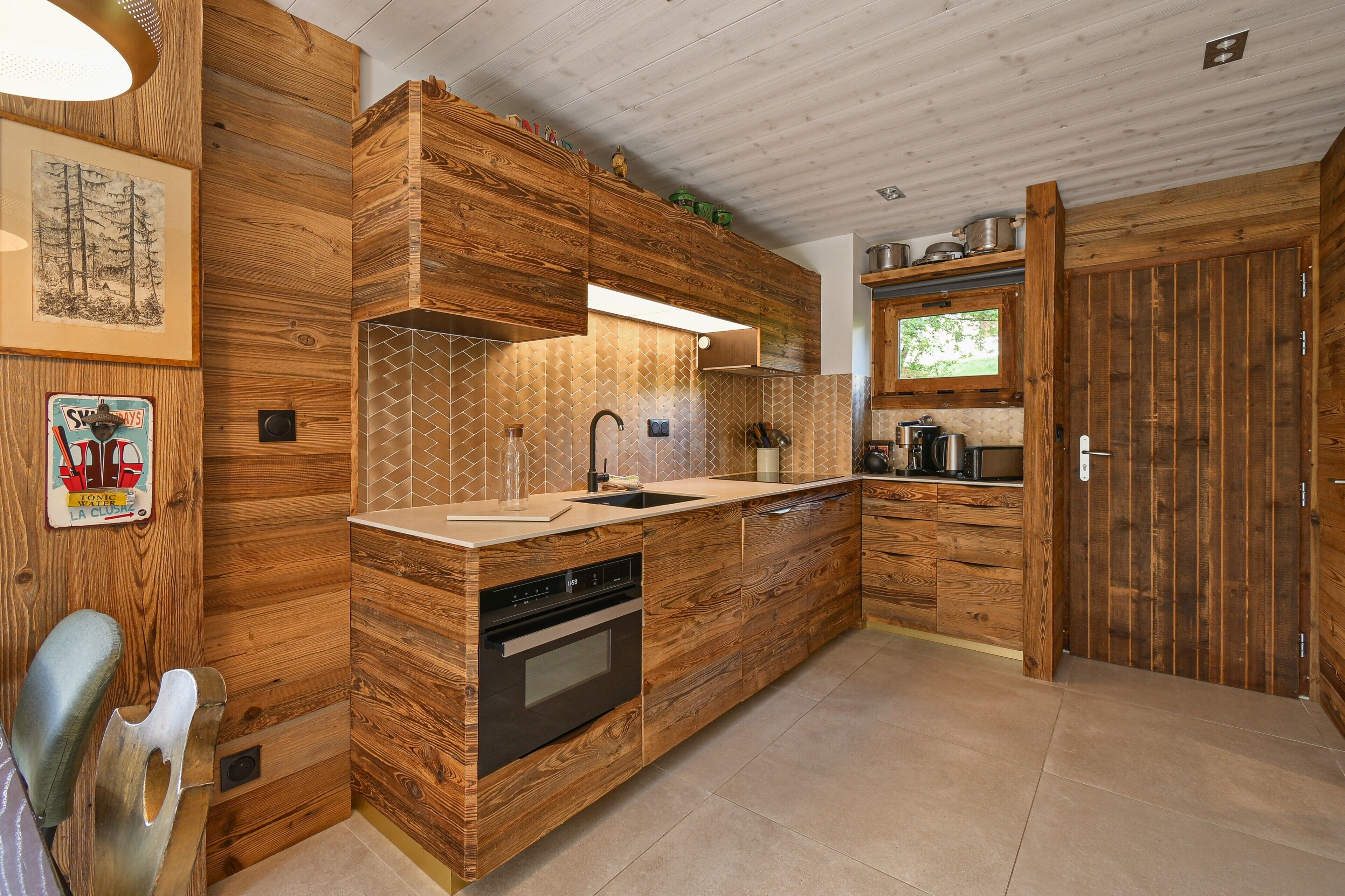A kitchen with wooden cabinetry, a built-in oven, and a window above the sink.