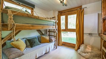 Une pièce confortable avec un lit superposé, un petit canapé avec des coussins, un tapis moelleux et une fenêtre avec des rideaux.
